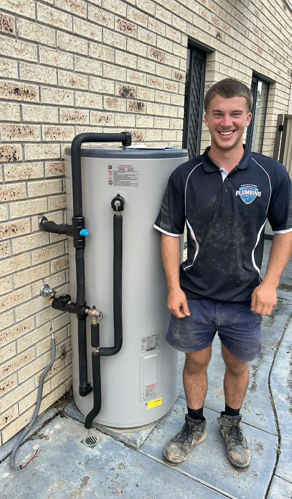 Gold Coast Plumbing Company plumber beside a hot water system